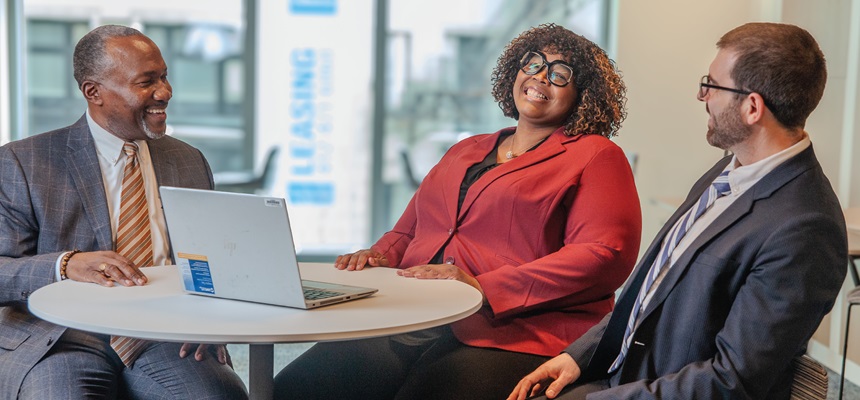 Business people sitting around a table smiling and talking while working together