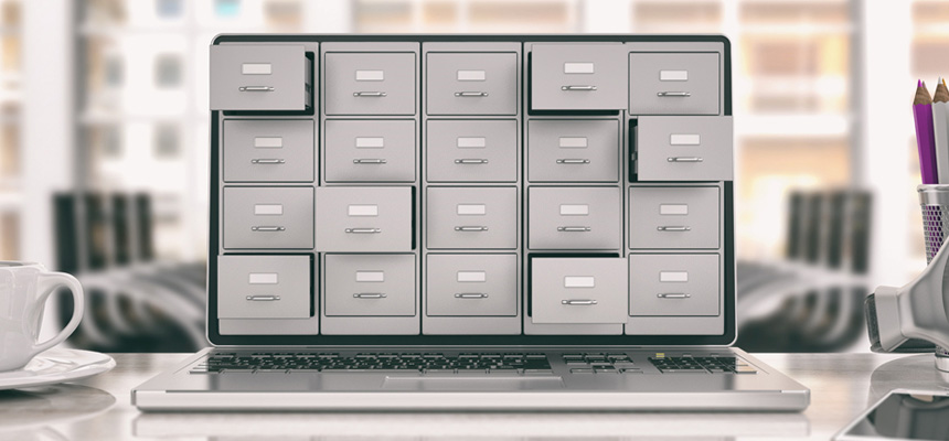 An open laptop sitting on a desk with open and closed file cabinet drawers covering its screen.