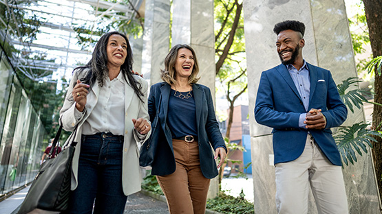 Three laughing professionals are walking outside, representing the positive and expert-driven partnerships that define HM Specialty's approach to delivering tailored reinsurance and excess coverage solutions.