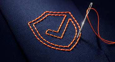 A needle stitches a shield design with a checkmark, showing custom-fit protection for Stop Loss insurance.