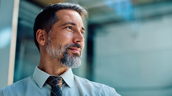 A middle-aged man looks thoughtfully to the side, representing employers considering self-funding and Stop Loss insurance.