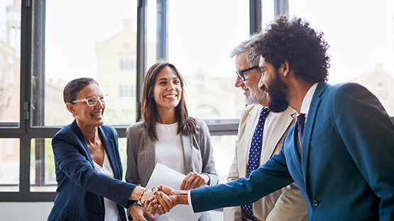 Two senior and two middle-aged adults smiling and shaking hands, representing the financial protection of Stop Loss coverage.